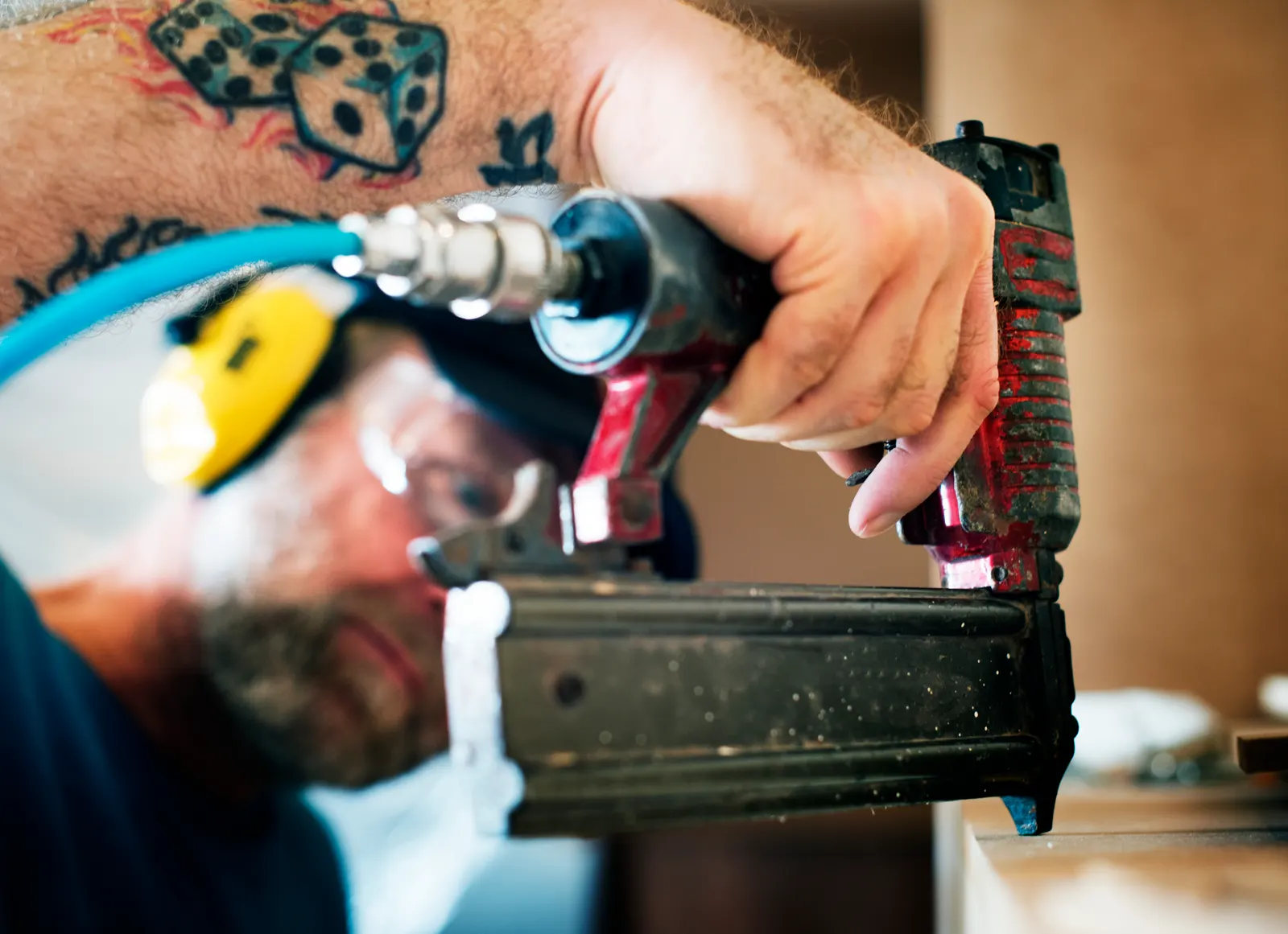 Carpenter driving finish nails with a pneumatic nail gun during a house renovation