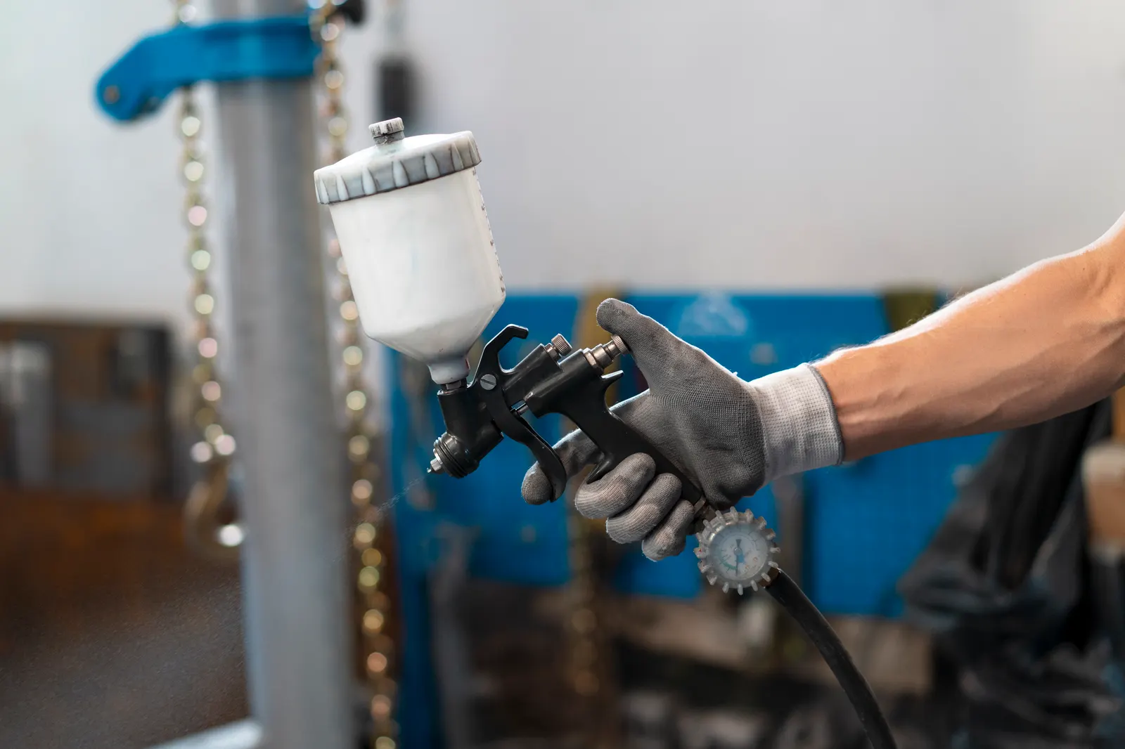 Auto body painter spraying with an air-powered paint gun